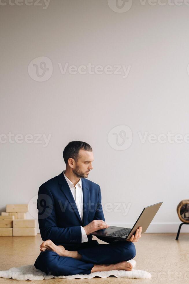 A man in a formal suit works sitting in a fitness room on a laptop photo