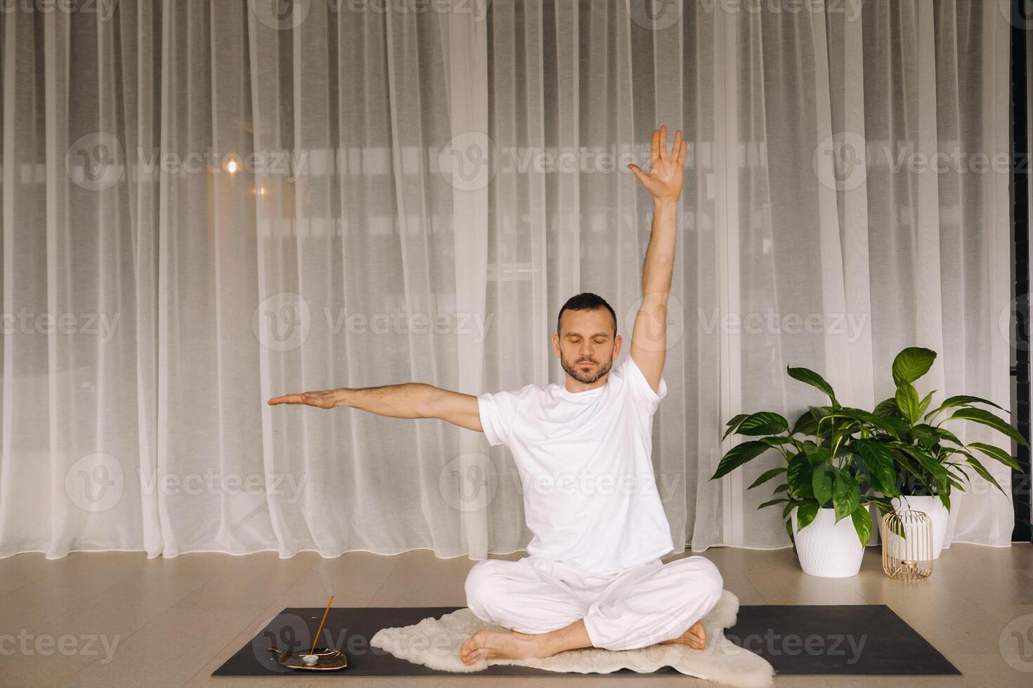 a man in white sportswear is doing yoga with a fitness room. the concept of a healthy lifestyle photo