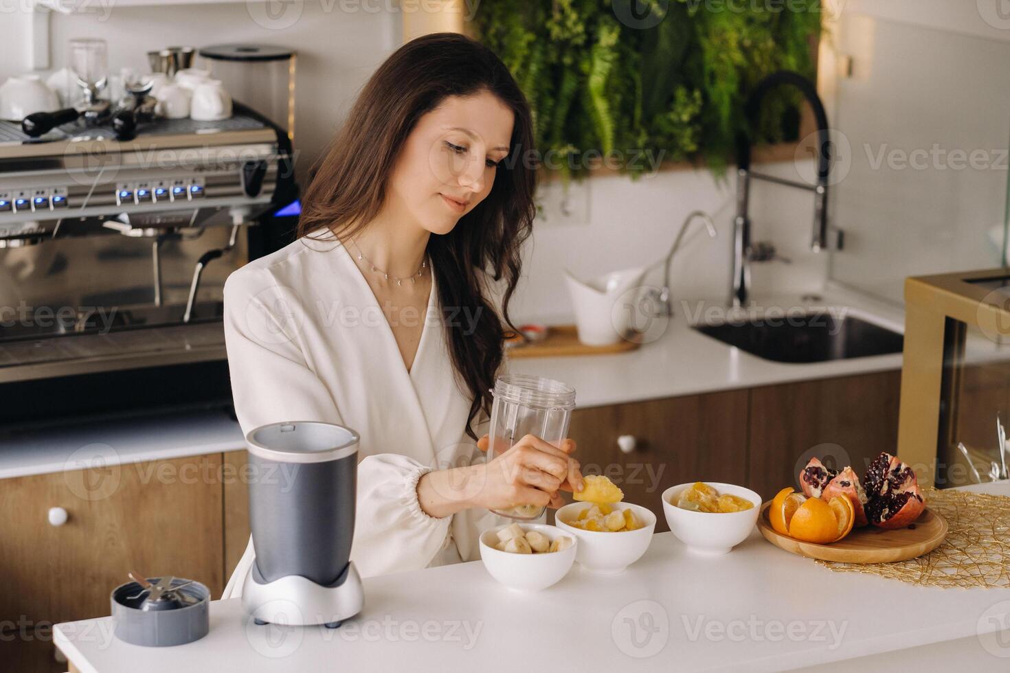 a girl makes a detox cocktail of fruit in the kitchen . Diet for weight loss photo