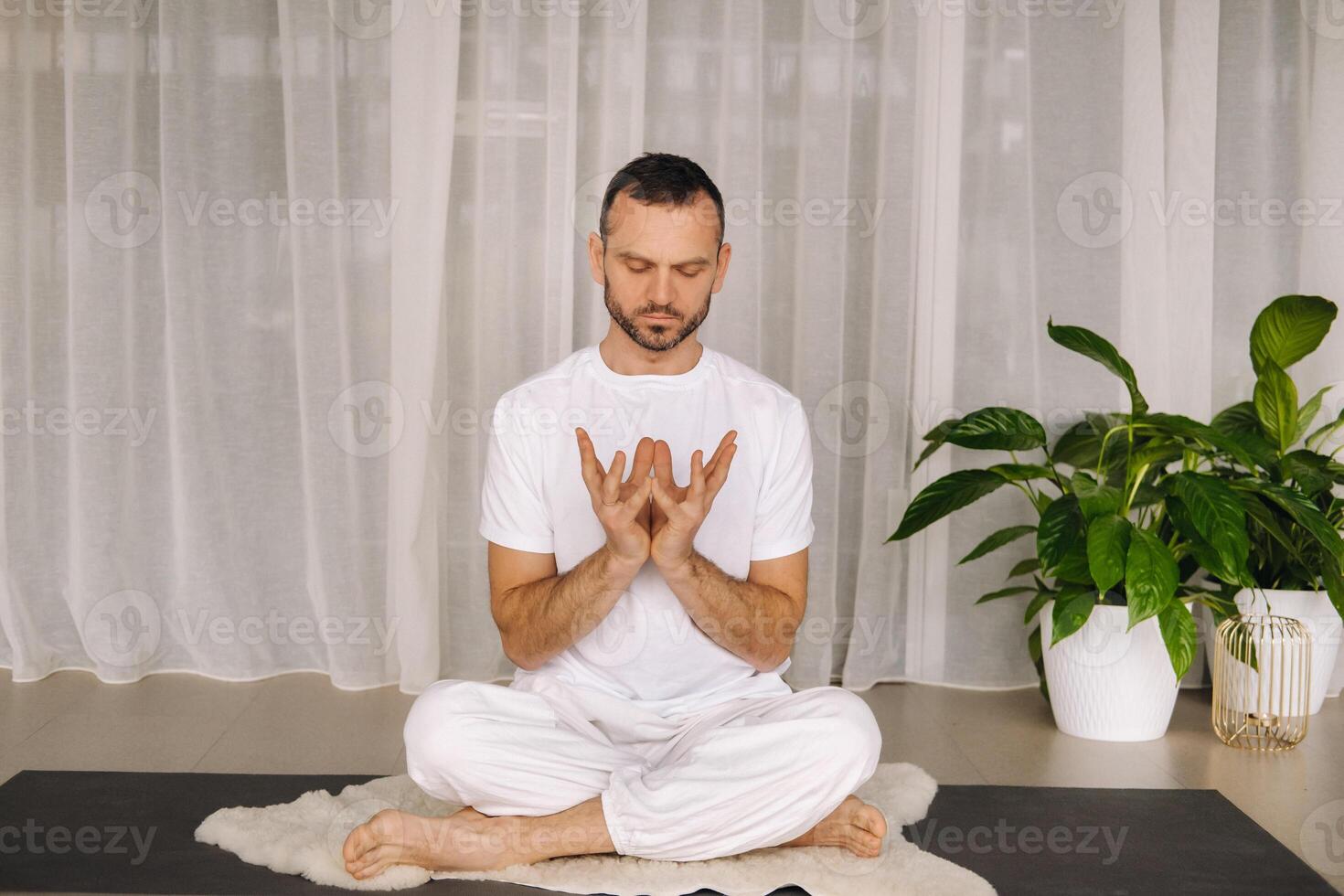 un hombre en blanco ropa de deporte es haciendo yoga con un aptitud habitación. el concepto de un sano estilo de vida foto