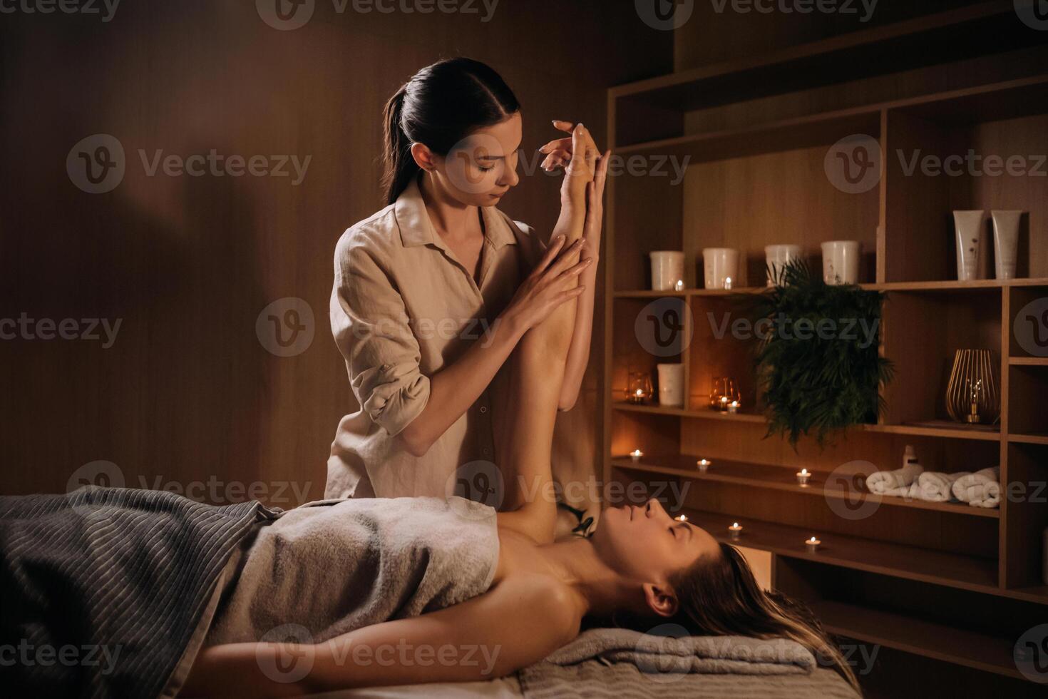 A masseuse gives a hand massage to a woman in a spa center. A professional masseur massages the hand of a girl lying in a spa center photo