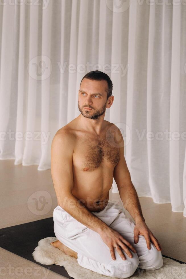 un hombre con un desnudo torso lo hace yoga en un aptitud habitación. el concepto de un sano estilo de vida foto