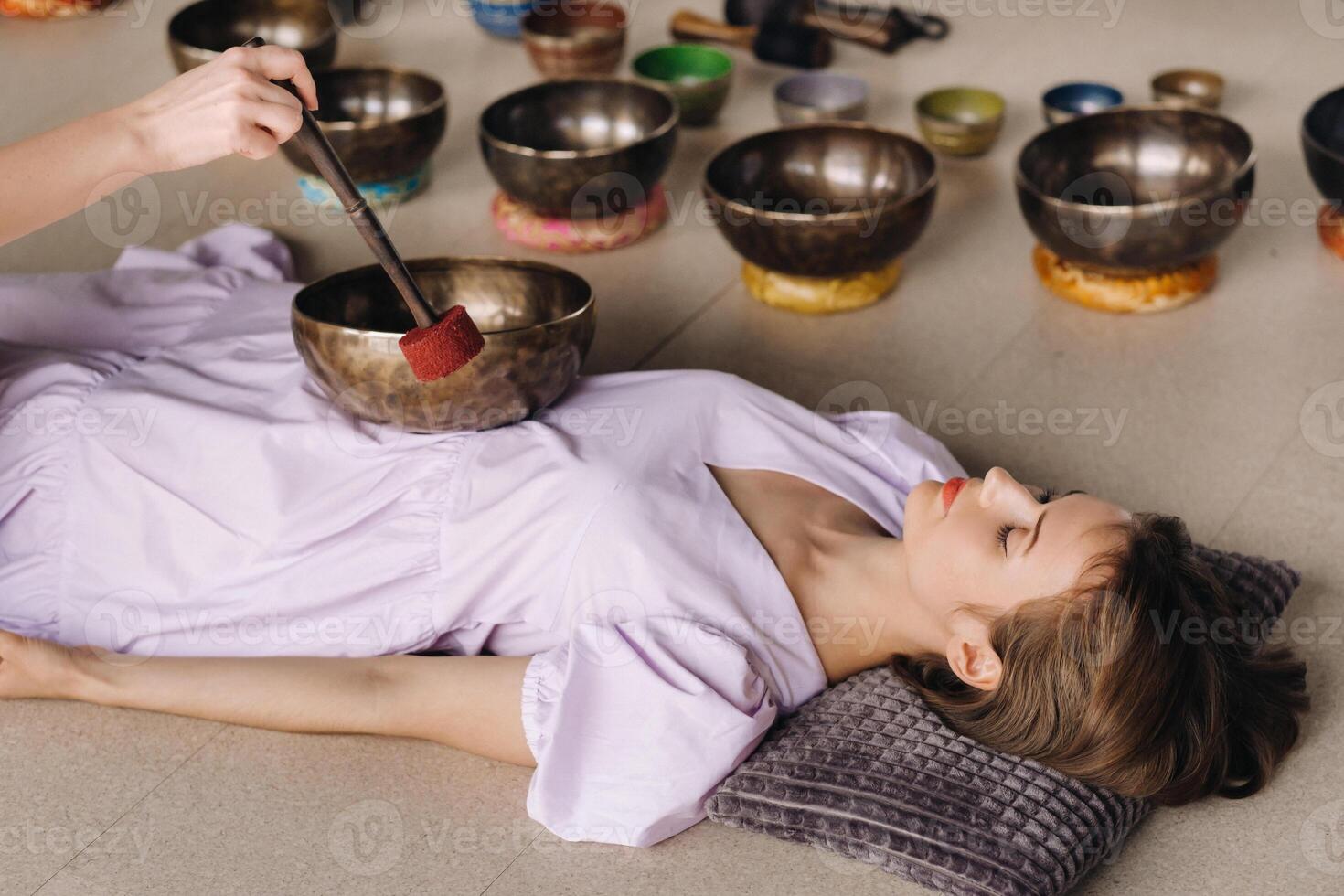 The copper singing bowl of the Nepalese Buddha in the spa. A young beautiful woman is doing a massage with singing bowls in a spa salon against the backdrop of a waterfall photo