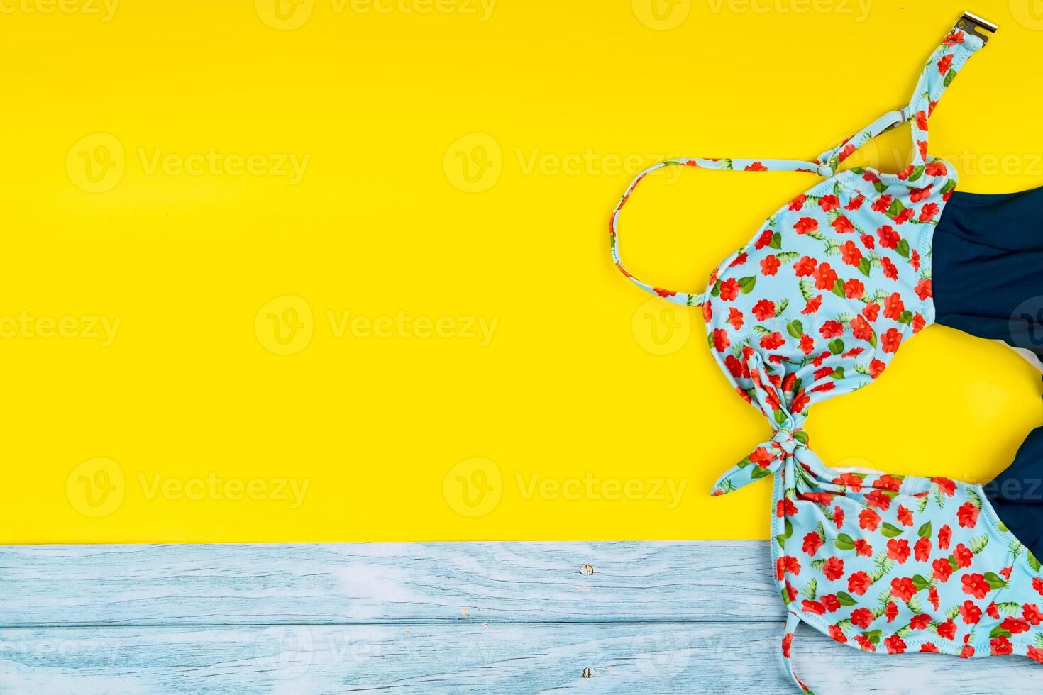 Top view of the swimsuit lying on a blue wooden and yellow background.Summer vacation concept photo
