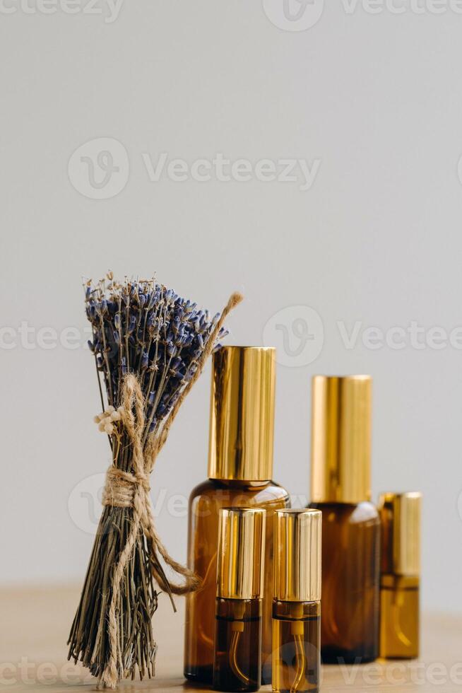 Essential oil in one bottle and dried lavender standing on the surface photo