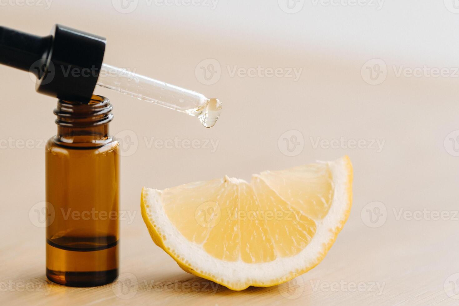 Essential oil in one bottle and lemon lying on the surface photo