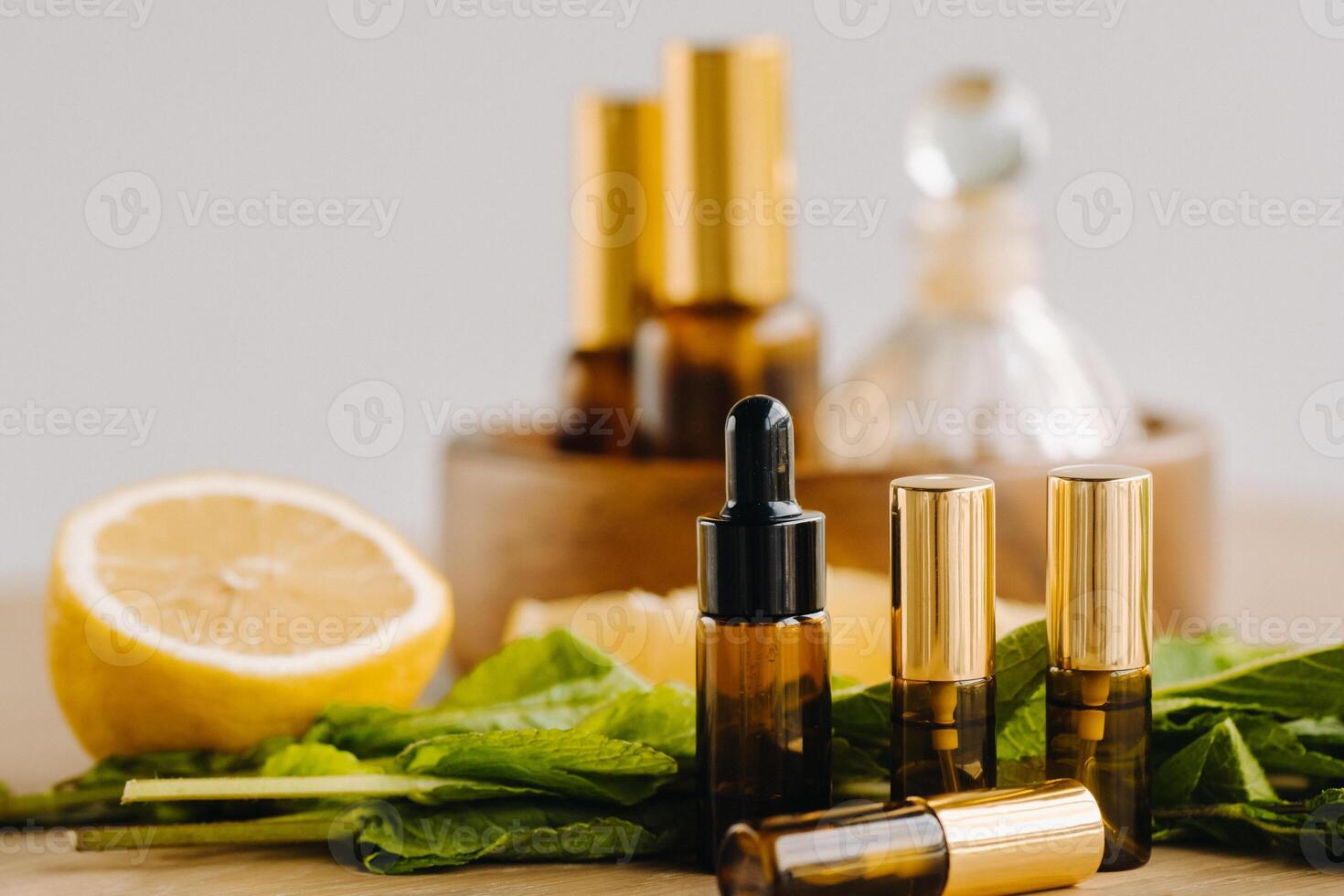 Essential oil in bottles with lemon and mint fragrance lying on a wooden surface photo