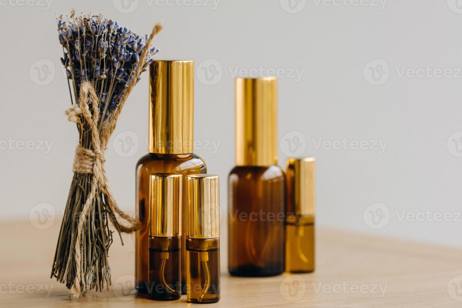 Essential oil in one bottle and dried lavender standing on the surface photo