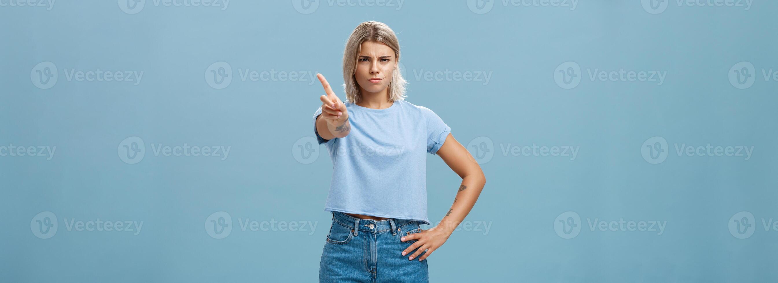 usted mejor no hacer él. de aspecto serio disgustado estricto mayor hermana con justa pelo y bronceado piel ceñudo participación mano en cintura sacudida índice dedo en prohibir o detener gesto terminado azul antecedentes foto