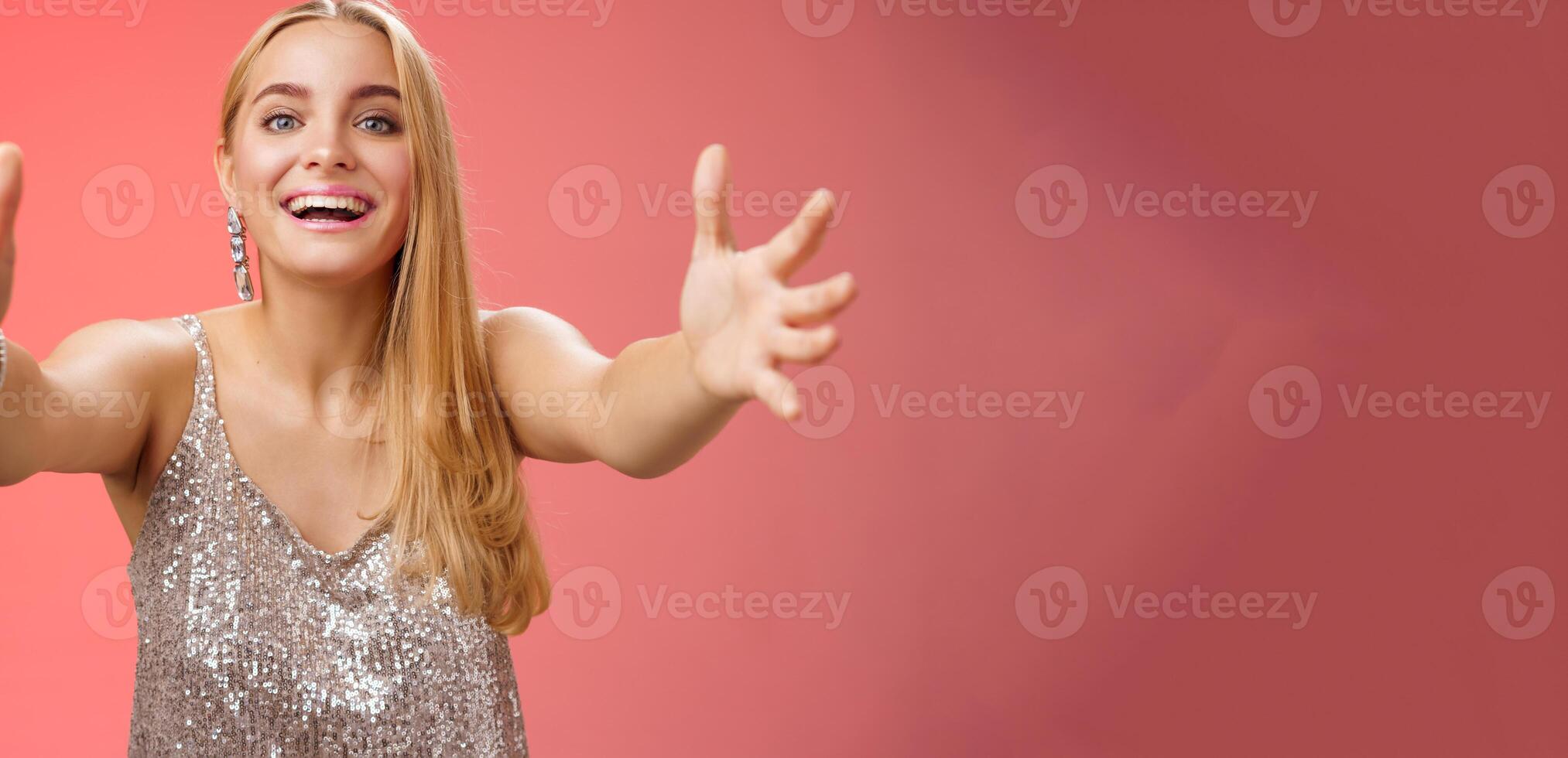 Hospitable charming nice young blond woman wanna hug come closer camera extend arms welcoming embracing cuddling being clingy smiling delighted standing amused red background photo