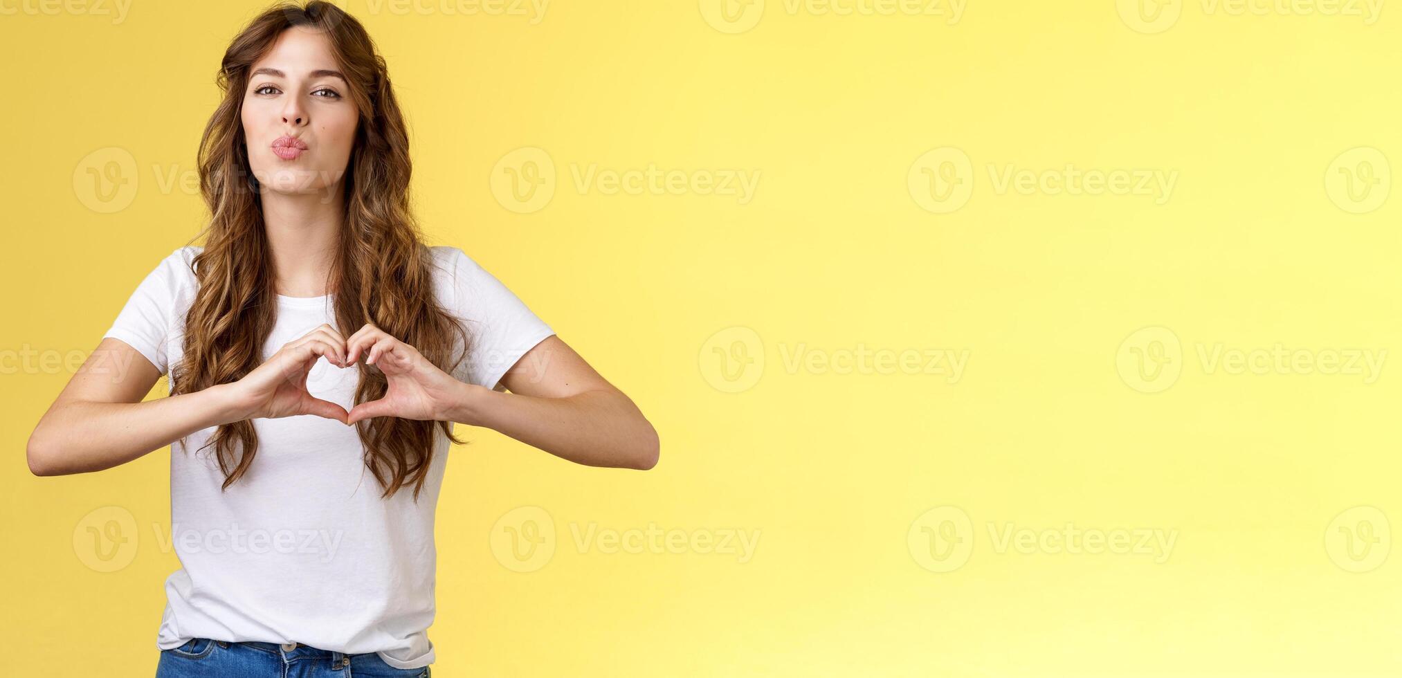 Passionate sensual attractive girlfriend express love sympathy show heart sign near chest folding lips kiss sending muah camera look admiration confess deep romantic feelings adore you photo