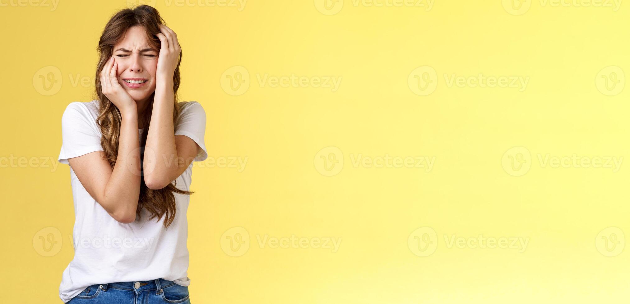 Offended silly timid insecure girl crying feel scared insulted close eyes whining grab head being victim sorry herself after huge quarrel sobbing stand yellow background upset distressed photo