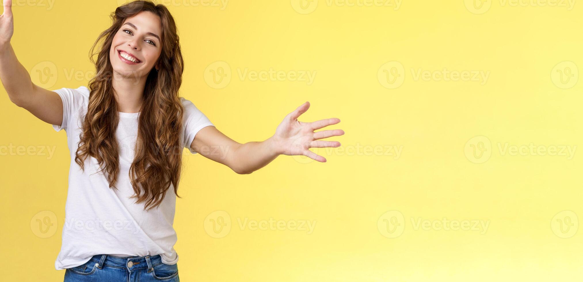 Wanna hold you tight. Romantic sincere gentle cute caucasian girl long beautiful curly hair tilt head lovely extend arms give cuddles wanna hug friend embracing dear guests yellow background photo