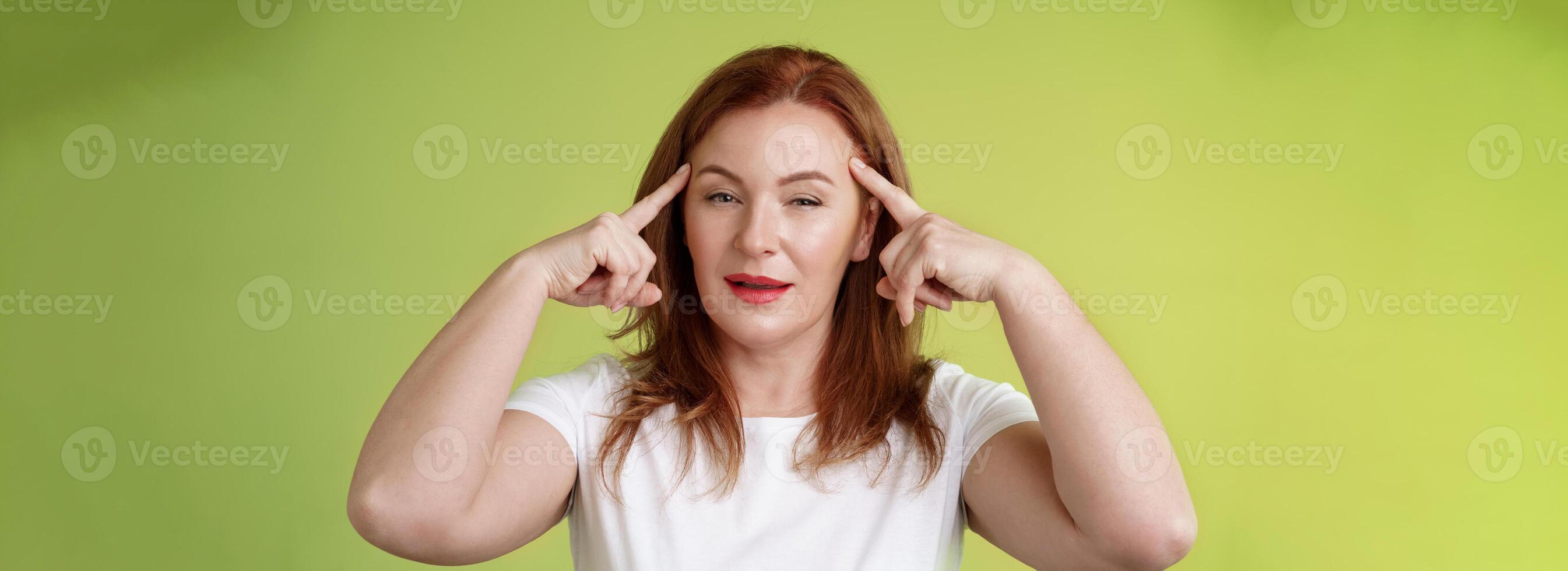 inteligente elección. intrigado pensativo guapo positivo pelirrojo creativo de edad mediana mujer toque templos bizco reflexionando informacion pensando utilizar mental poder leer mentes estar verde antecedentes foto