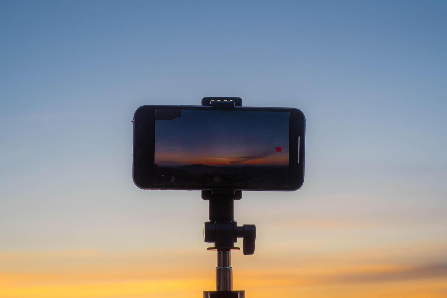 A smartphone is recording the sun setting over a mountain range. photo