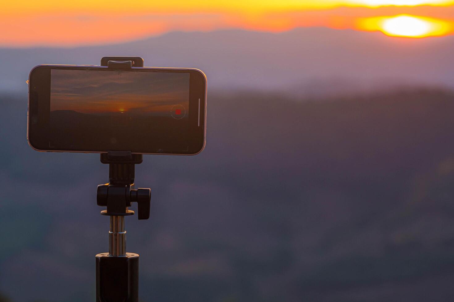 A smartphone is recording the sun setting over a mountain range. photo