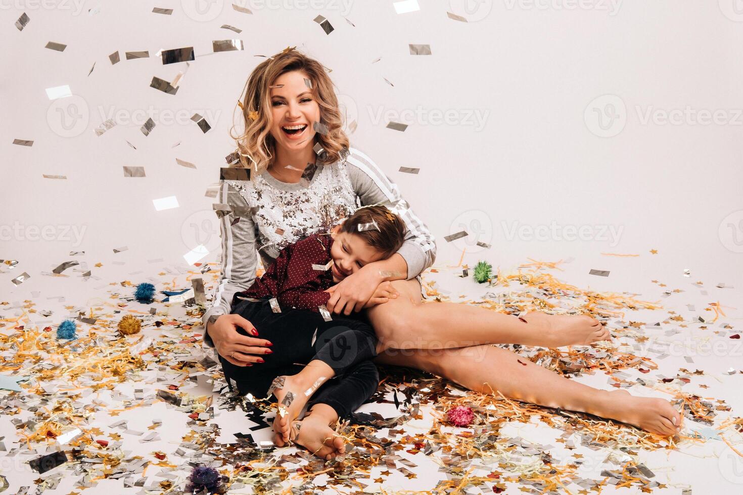 Portrait of a happy mother and son on a white background in confetti photo