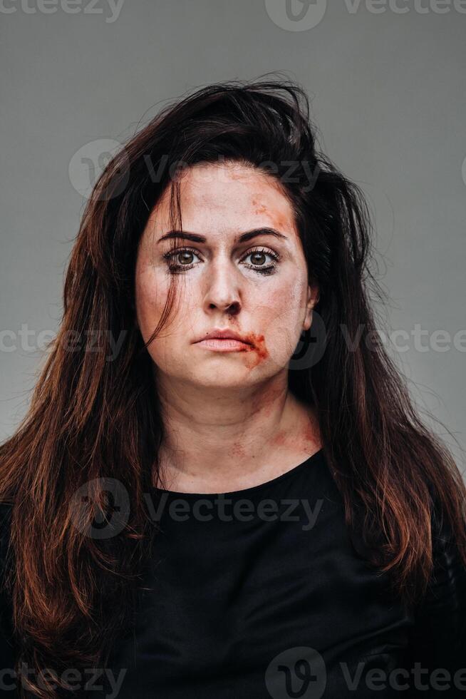 a battered woman in black clothes on an isolated gray background. Violence against women photo