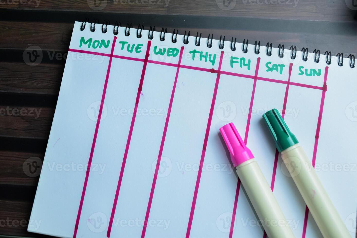 Concept of Weekly Calendar write on book isolated on Wooden Table. photo