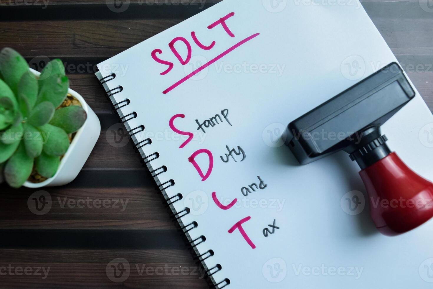 Concept of SDLT - Stamp Duty Land Tax write on book isolated on Wooden Table. photo