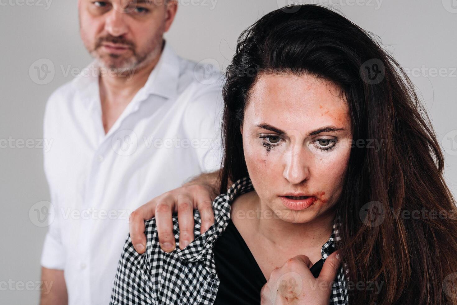 A woman beaten by her husband standing behind her and looking at her aggressively. Domestic violence photo