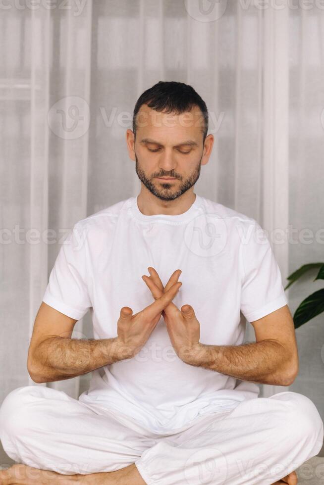 a man in white sportswear is doing yoga with a fitness room. the concept of a healthy lifestyle photo