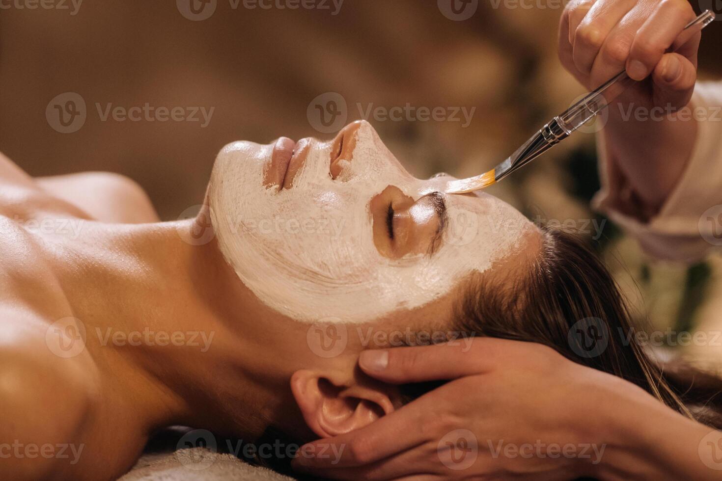A cosmetologist makes a mask for a woman's face to rejuvenate the skin. Cosmetology photo