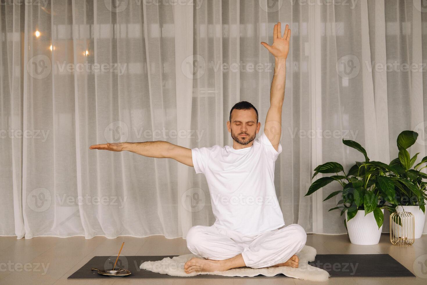 a man in white sportswear is doing yoga with a fitness room. the concept of a healthy lifestyle photo