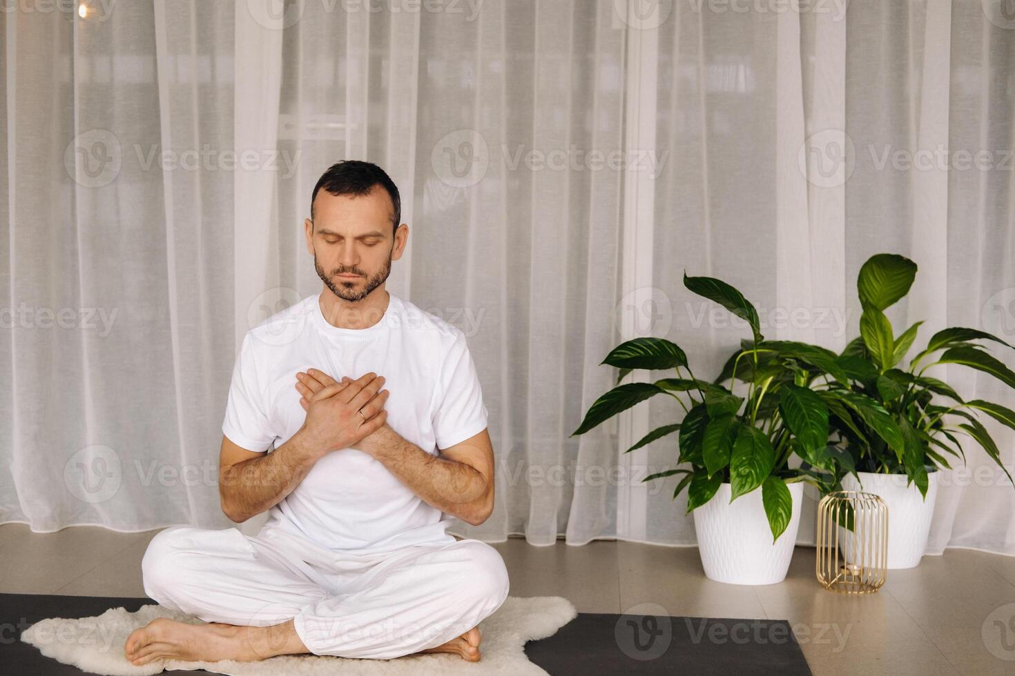 a man in white sportswear is doing yoga with a fitness room. the concept of a healthy lifestyle photo