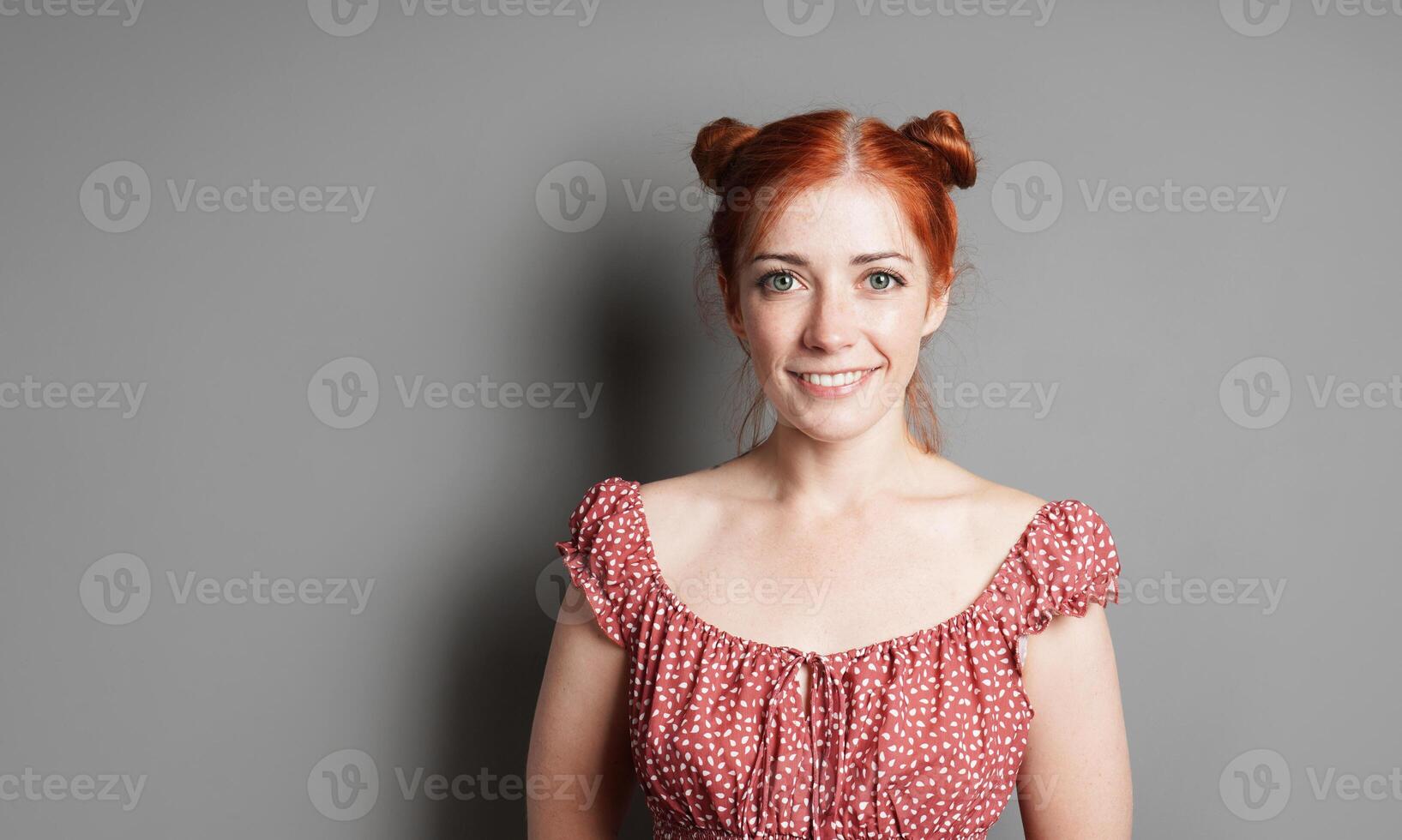 happy young woman with big toothy smile and red hair space buns photo