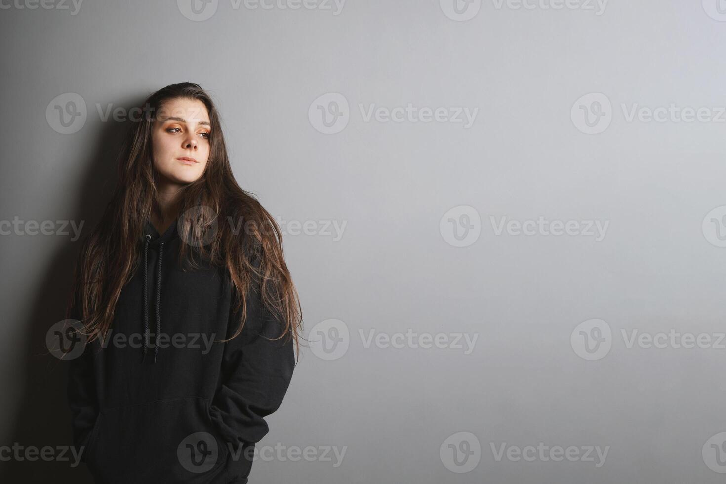 sad young woman leaning against wall looking to side in contemplation photo