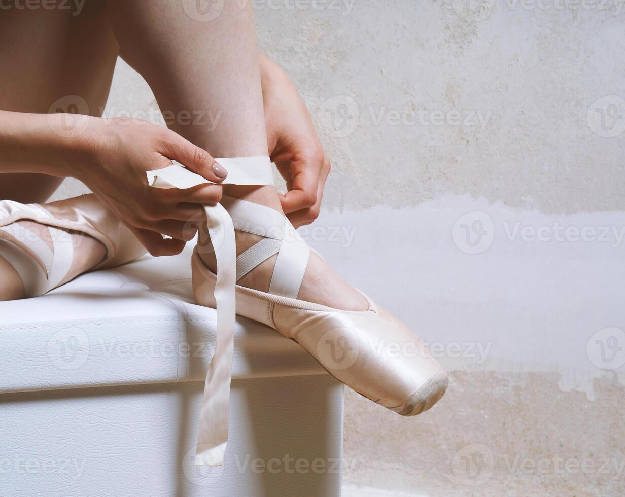 unrecognizable ballerina tying her pointe or ballet shoes photo