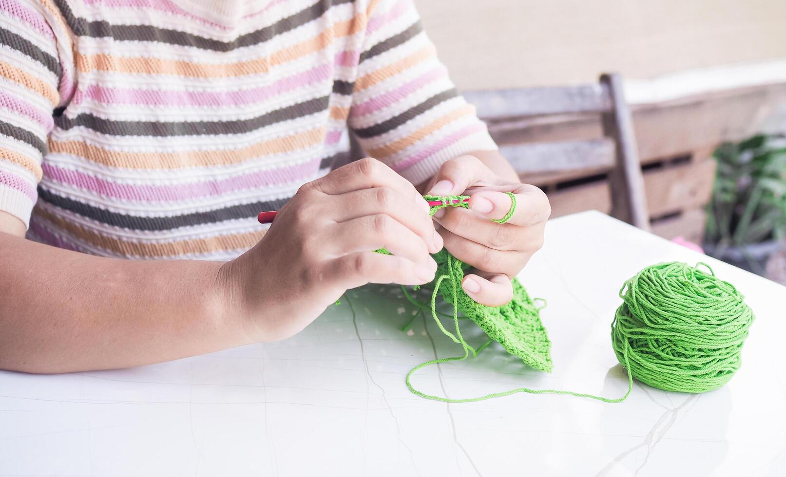 Close-up of woman hand knitting with green wool photo