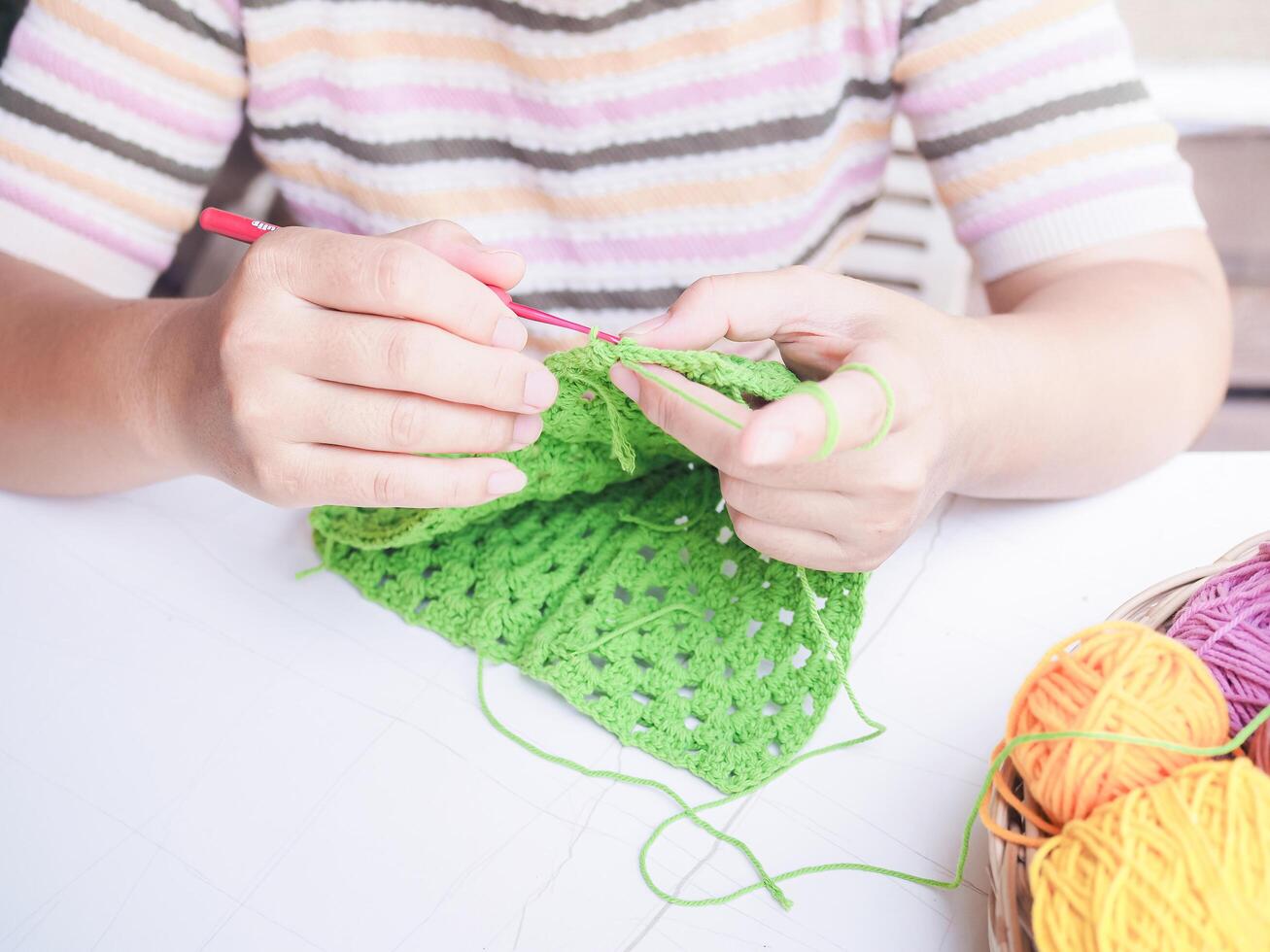 Close-up of woman hand knitting with green wool photo