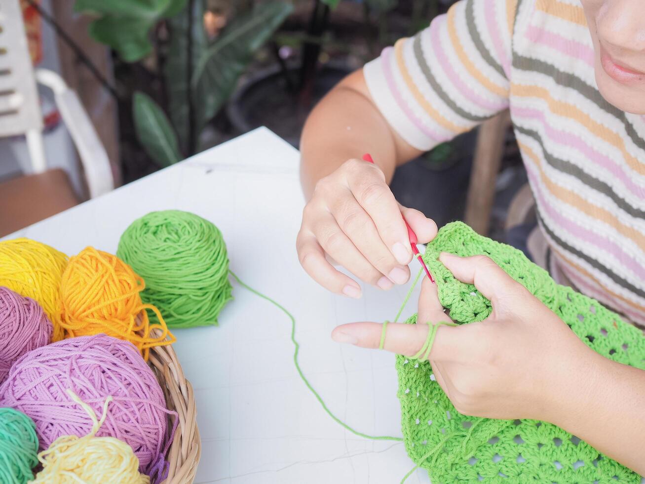 Close-up of woman hand knitting with green wool photo