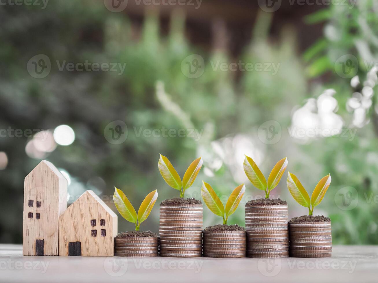 Miniature house and plants growing up on stack of coins. The concept of saving money for house, Property investment, House mortgage, Real estate. photo