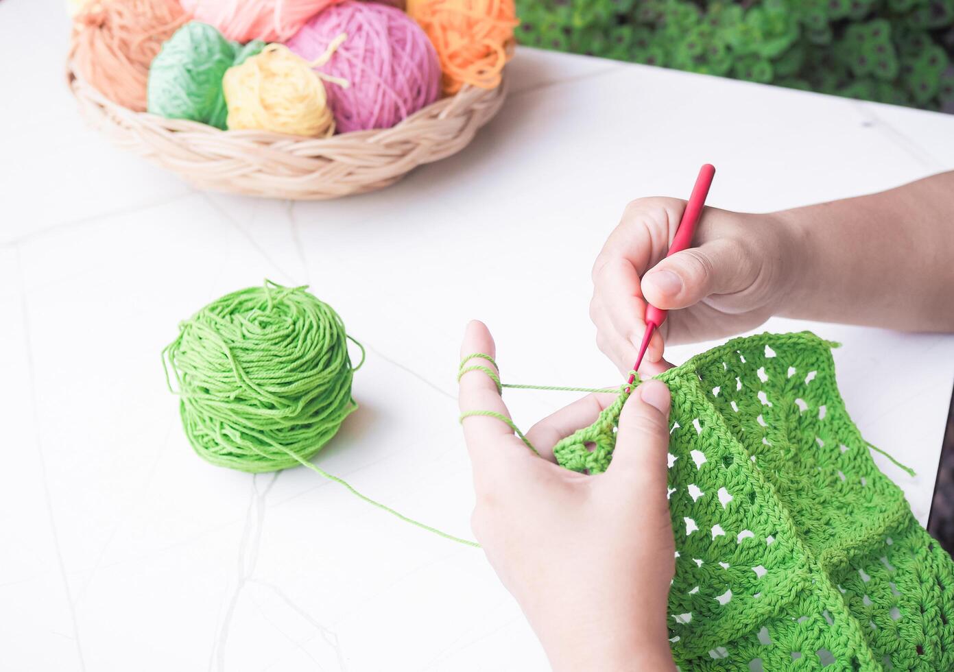 Close-up of woman hand knitting with green wool photo