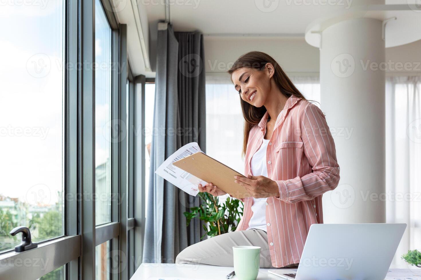 Beautiful woman freelancer noting information for planning project doing remote job via laptop computer. woman laughing while reading email on modern laptop device . photo