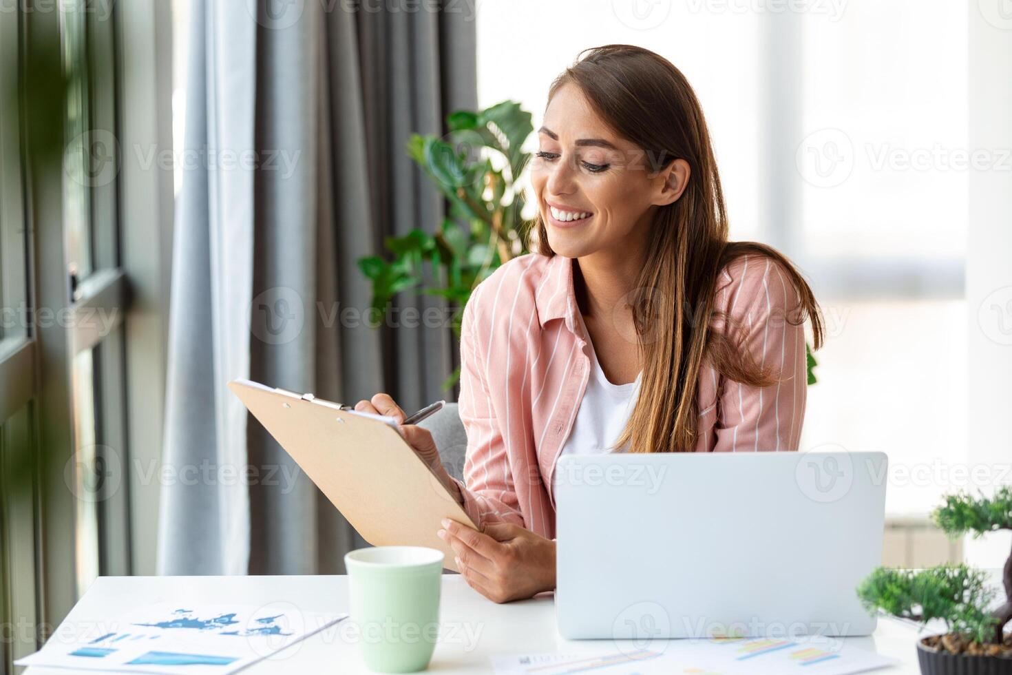 Remote job, technology and people concept - happy smiling young business woman with laptop computer and papers working at home office photo