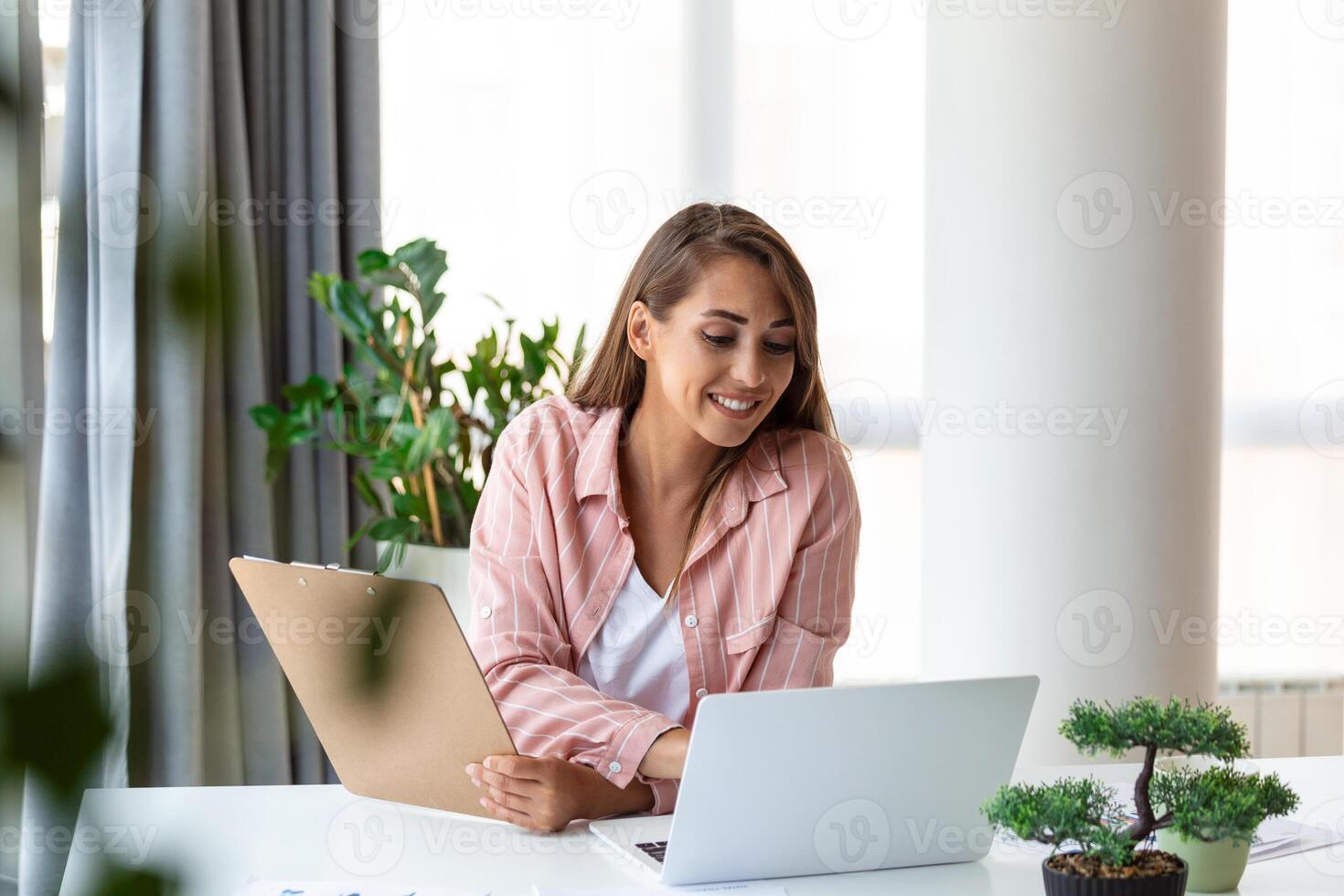 Remote job, technology and people concept - happy smiling young business woman with laptop computer and papers working at home office photo