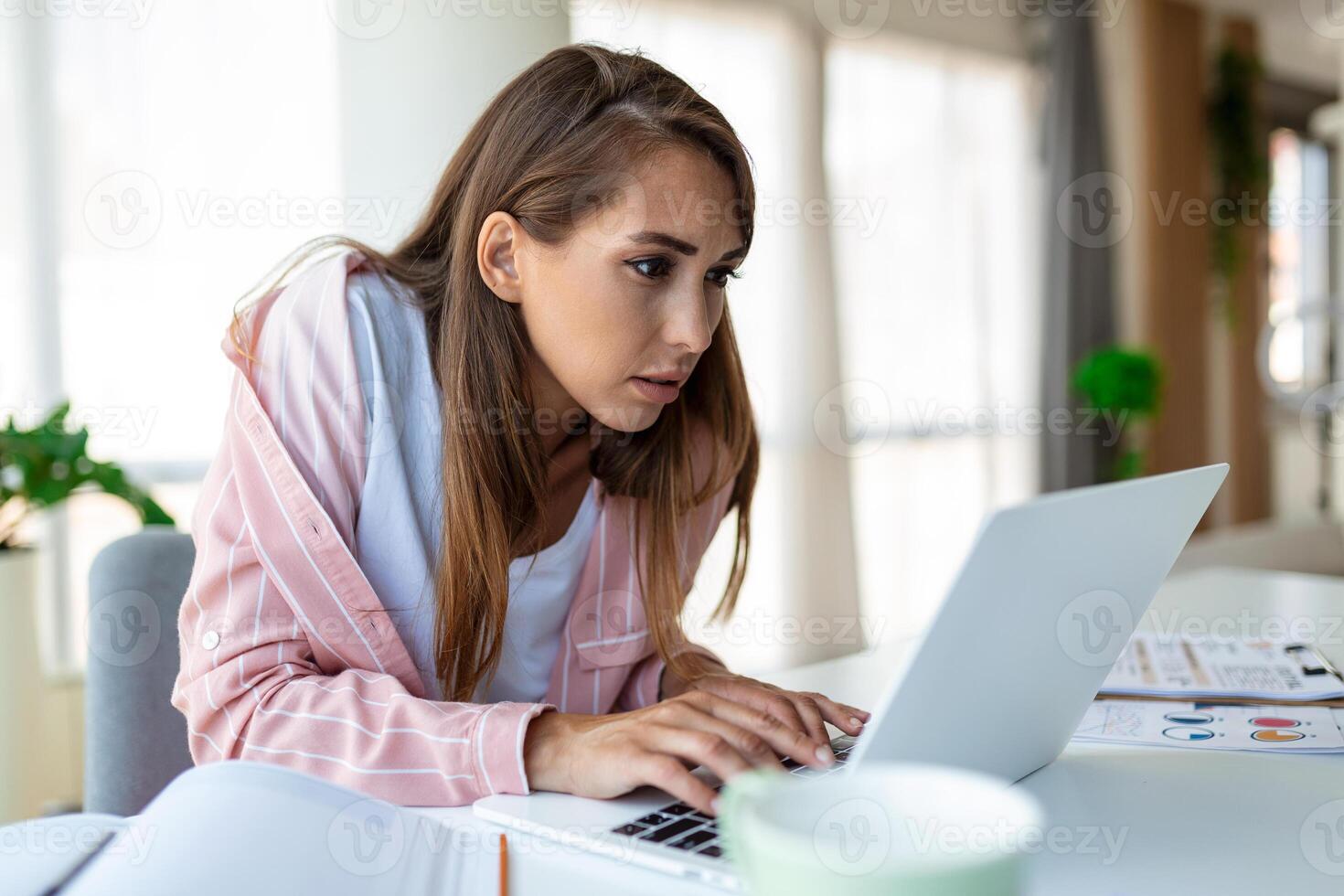 Young woman working laptop. Business woman busy working on laptop computer at office. Businesswoman sitting at bright modern work station and typing on laptop photo