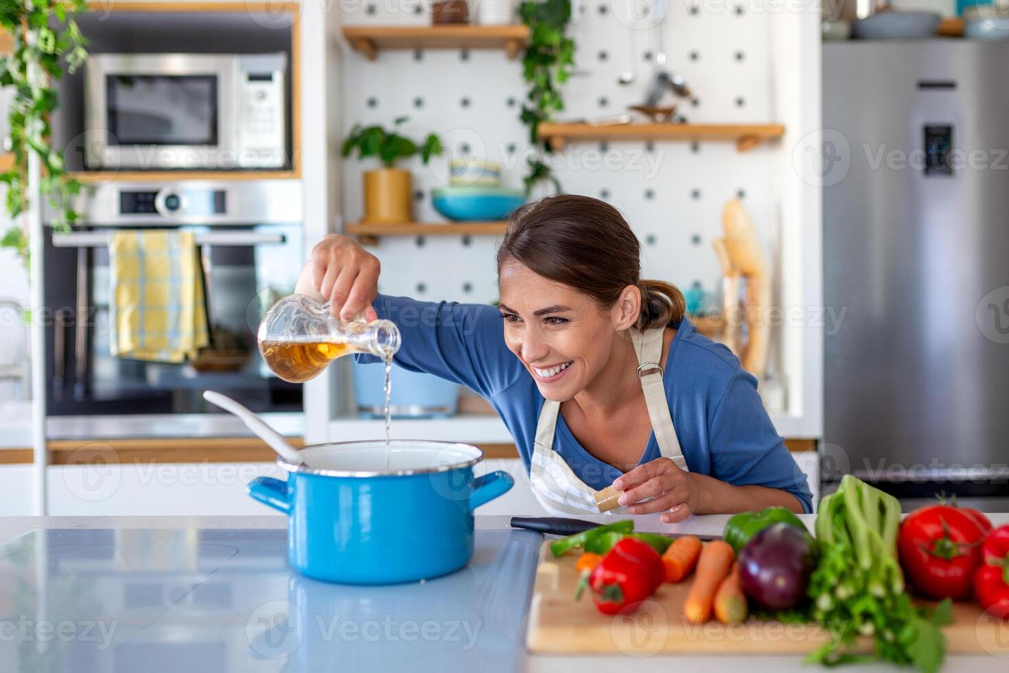 Ecstatic Young Lady Cooking and Sampling Dinner in a Pot, Positioned in a Sleek Kitchen at Home. Home Executive Preparing Wholesome Cuisine with a Grin. Household Management and Nutrient Intake. photo