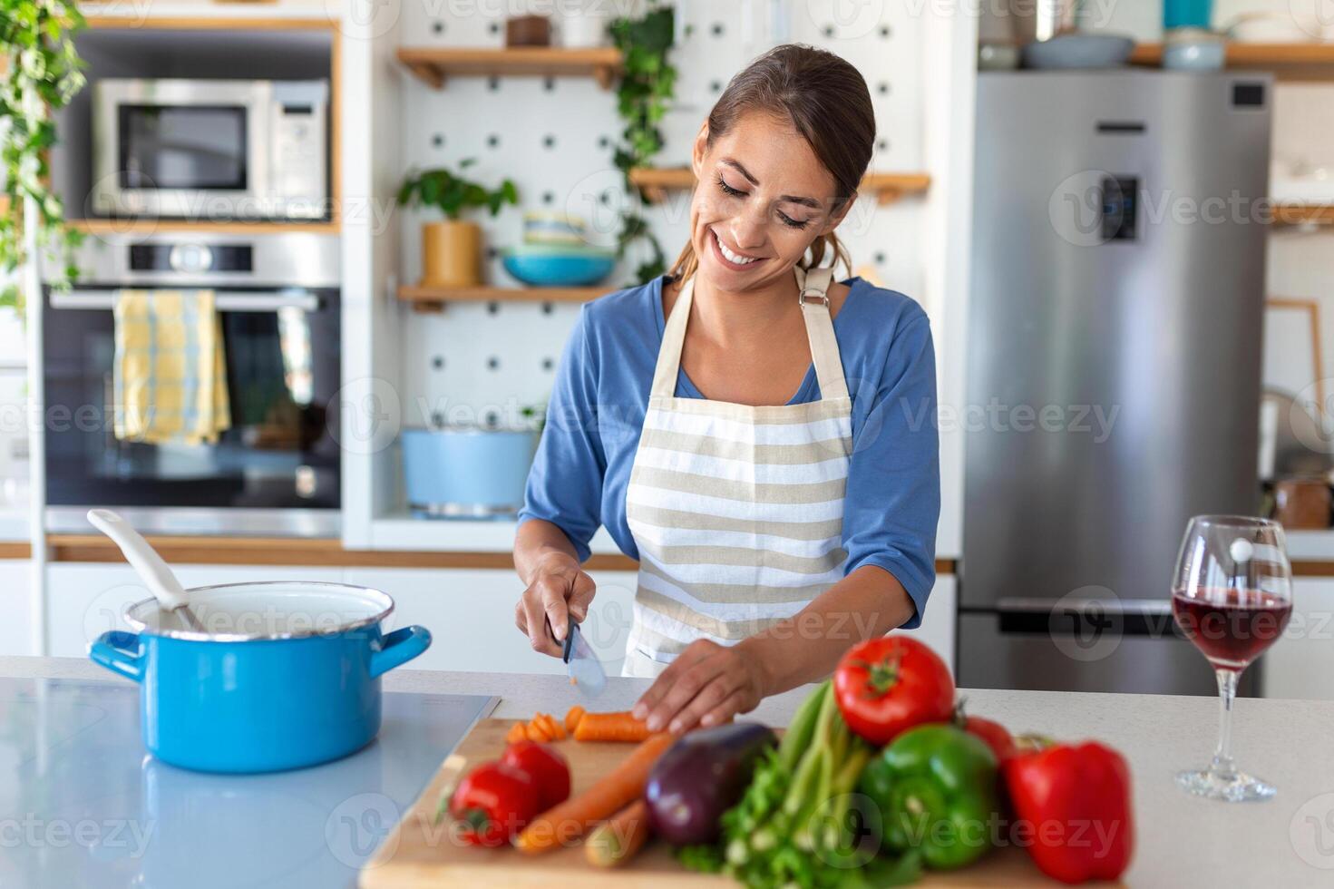 contento joven mujer Cocinando saboreo cena en un maceta en pie en moderno cocina a hogar. ama de casa preparando sano comida sonriente . casa y nutrición. dieta recetas concepto foto