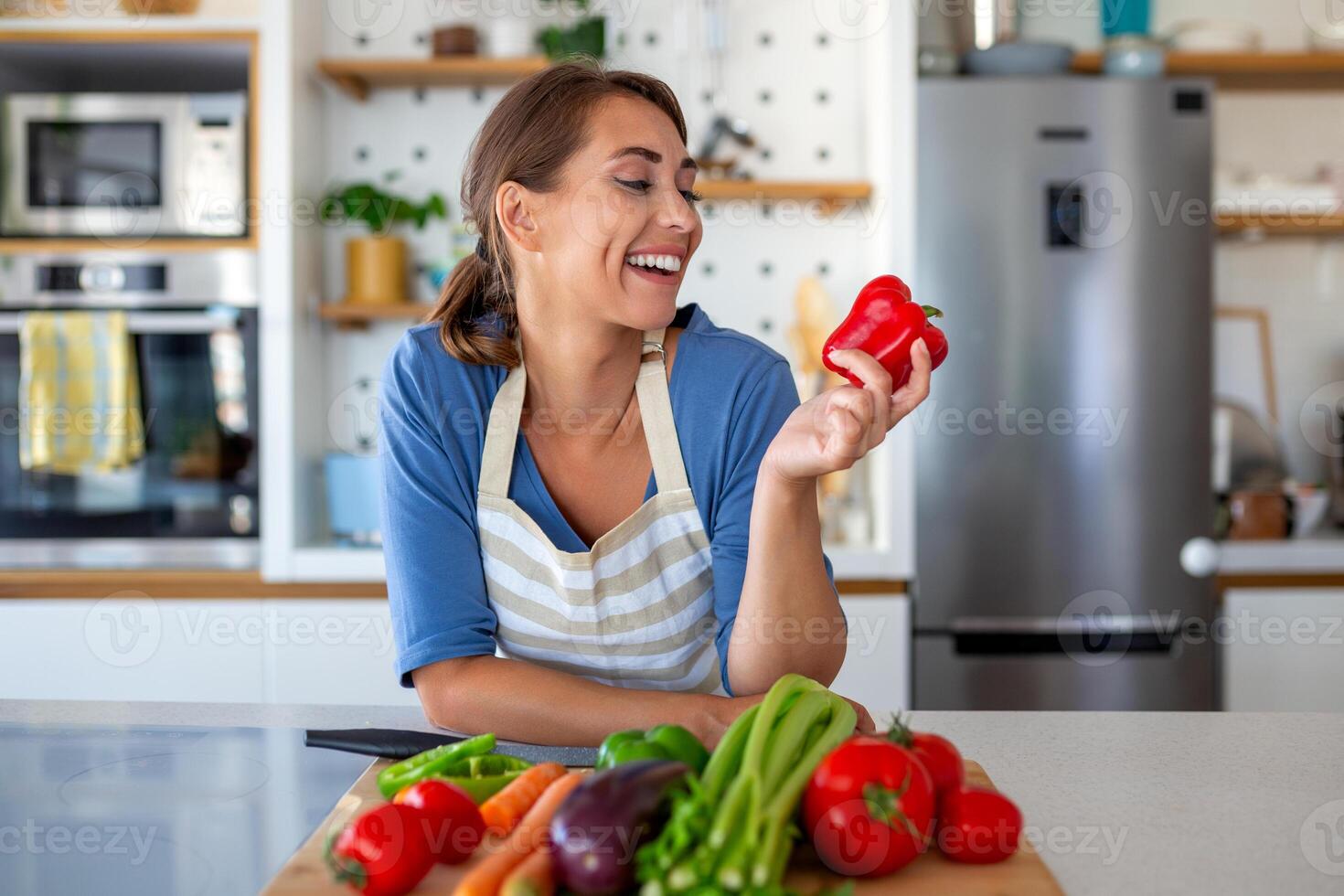 Cute happy young brunette woman in good mood preparing a fresh vegan salad for a healthy life in the kitchen of her home. photo