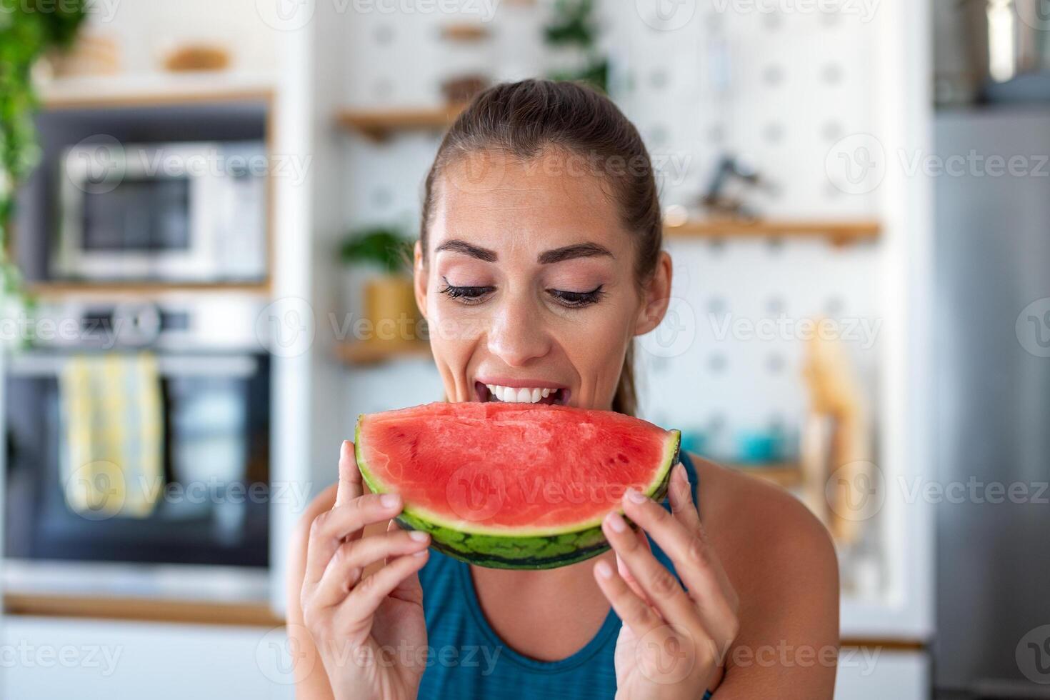 young woman in a delightful moment as she relishes a slice of watermelon. The vibrant colors of the fruit and her evident joy create a vivid portrait of a simple, yet deeply satisfying experience. photo