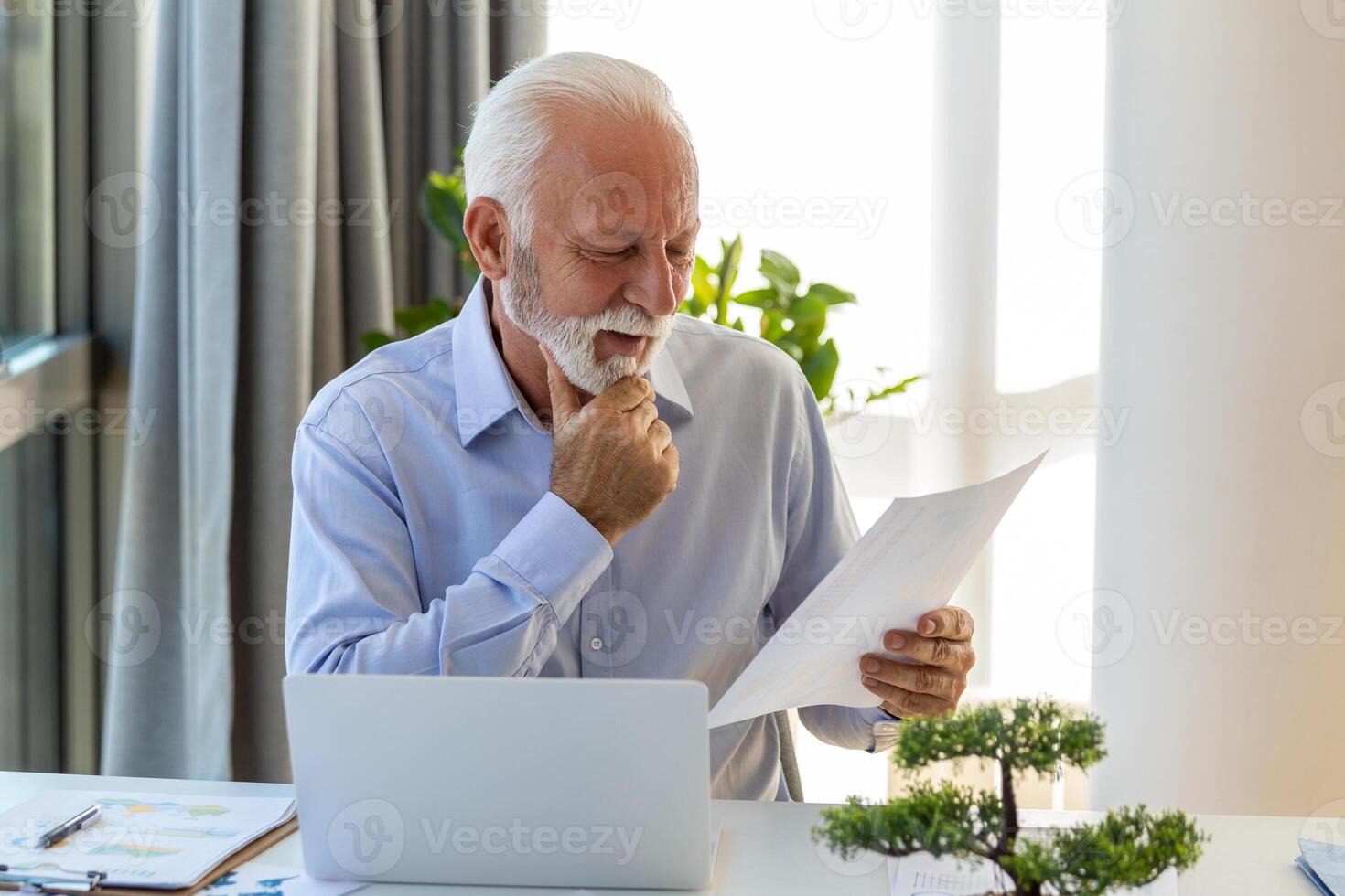 Financial advisor businessman using his laptop and doing some paperwork while sitting at desk and working. photo