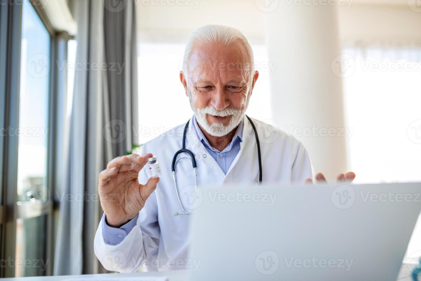 Doctor online. Senior medic talking to client on laptop computer from his office. Mature male therapist explaining medical treatment to patient through a video call with laptop in the consultation. photo