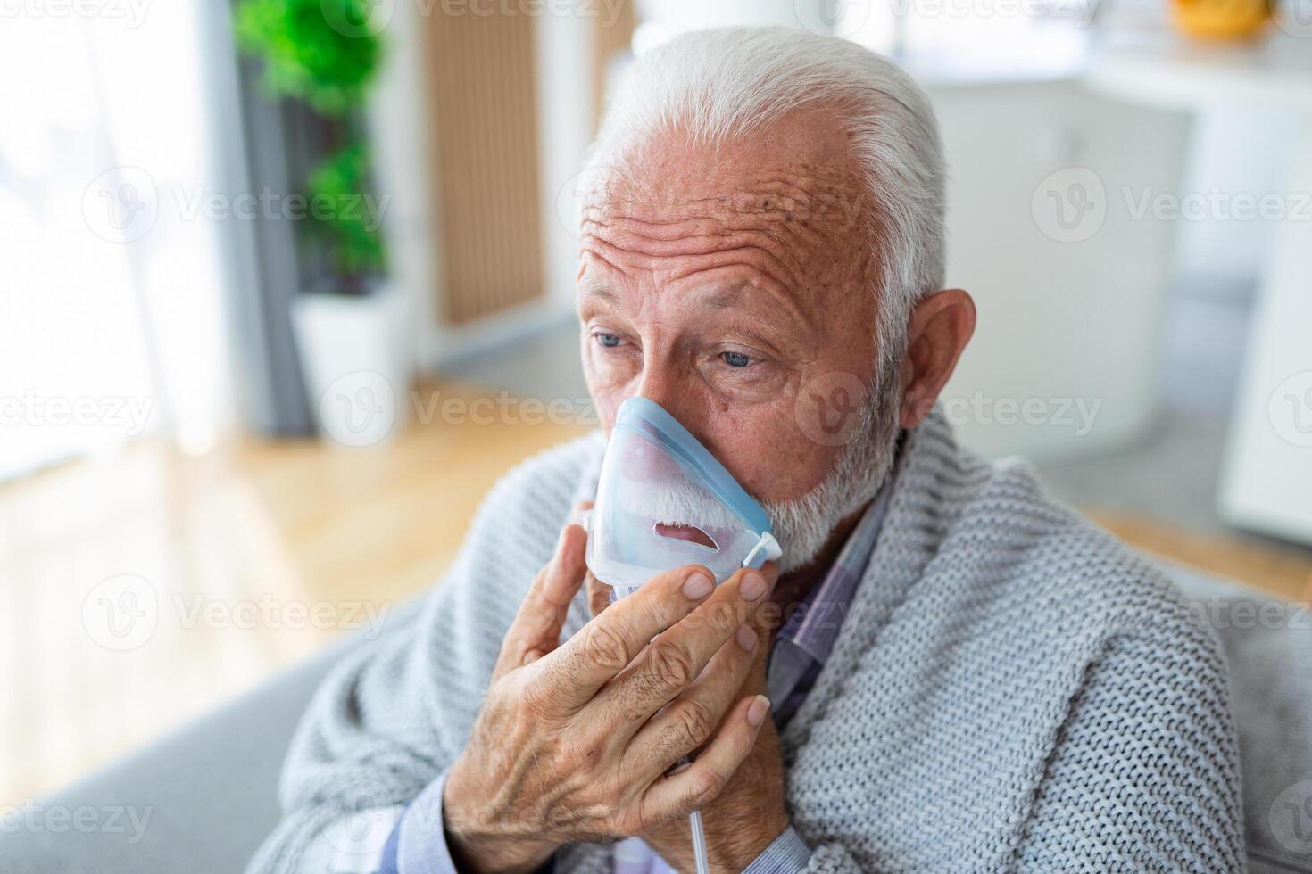 Sick elderly man making inhalation, medicine is the best medicine. Ill senior man wearing an oxygen mask and undergoing treatment for covid-19. Senior man with an inhaler photo