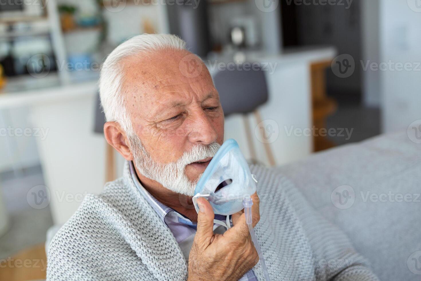 Sick elderly man making inhalation, medicine is the best medicine. Ill senior man wearing an oxygen mask and undergoing treatment for covid-19. Senior man with an inhaler photo