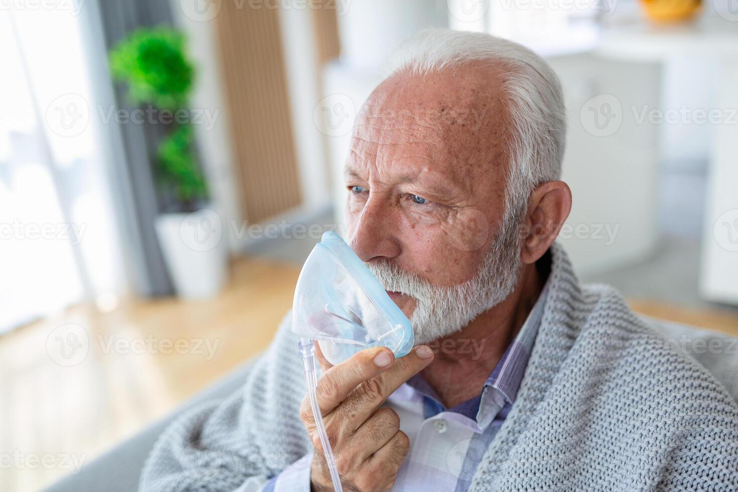 Sick elderly man making inhalation, medicine is the best medicine. Ill senior man wearing an oxygen mask and undergoing treatment for covid-19. Senior man with an inhaler photo